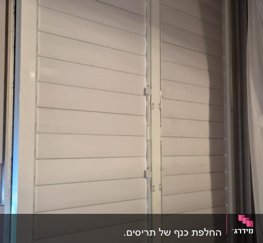 תריסים לבנים מותקנים על חלון